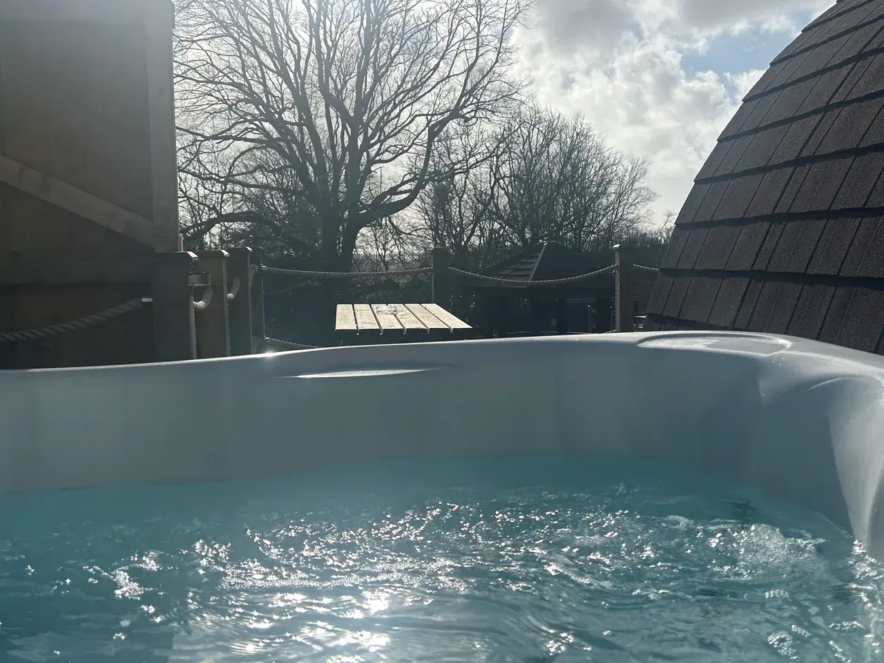Private hot tub on pod decking — warm bubbling water under clear skies
