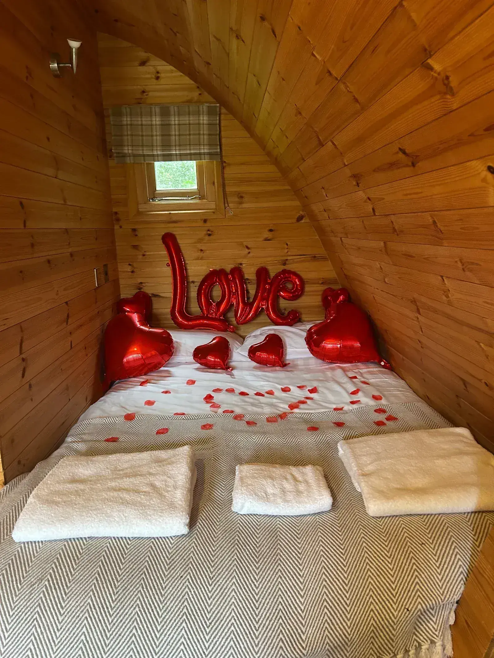 Romantic glamping pod interior with a 'Love' balloon display